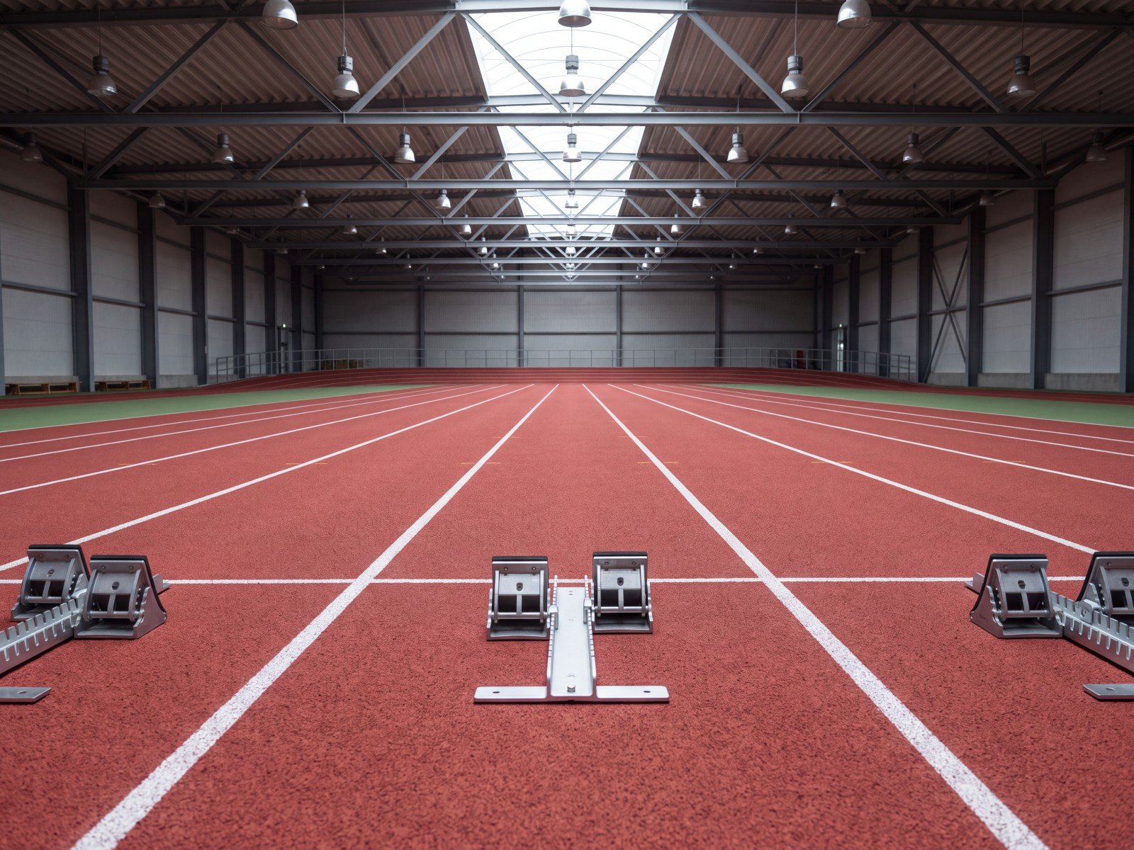 Pista de atletismo interior con superficie roja y tacos de salida