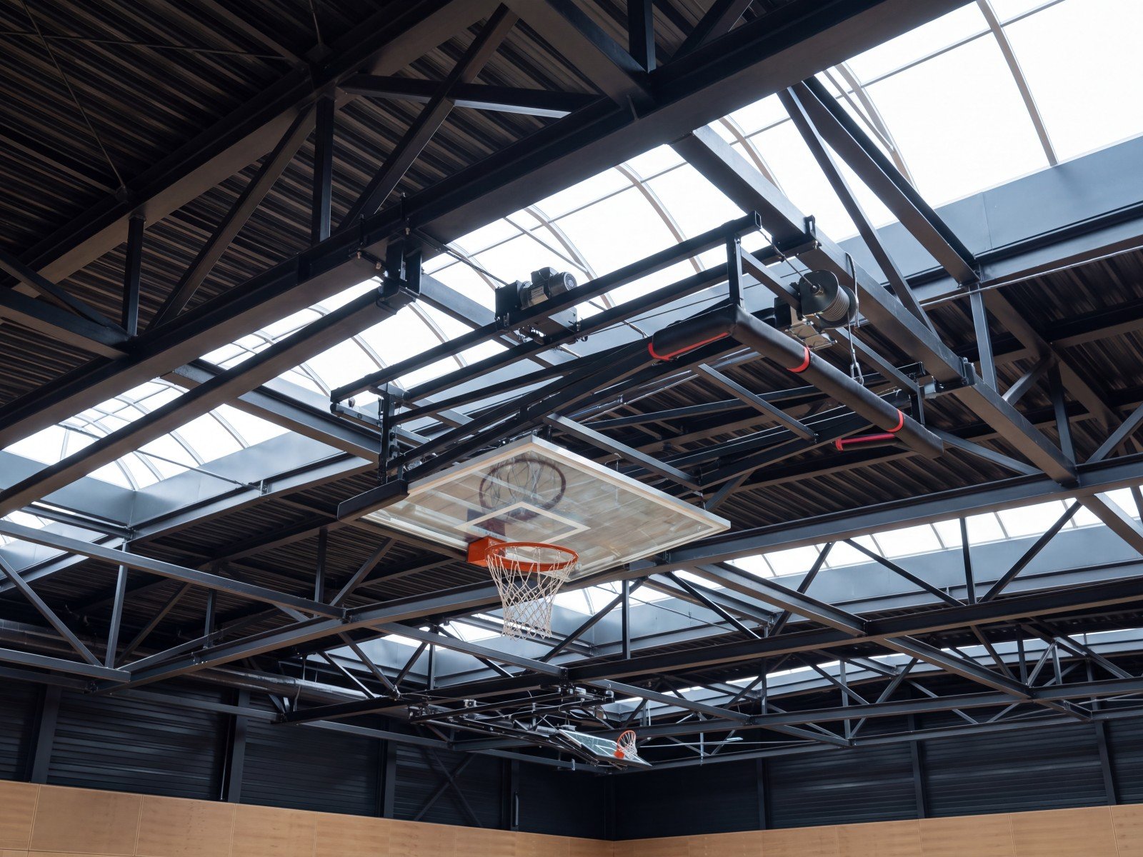 Canasta de baloncesto de techo plegada bajo la estructura de un pabellón