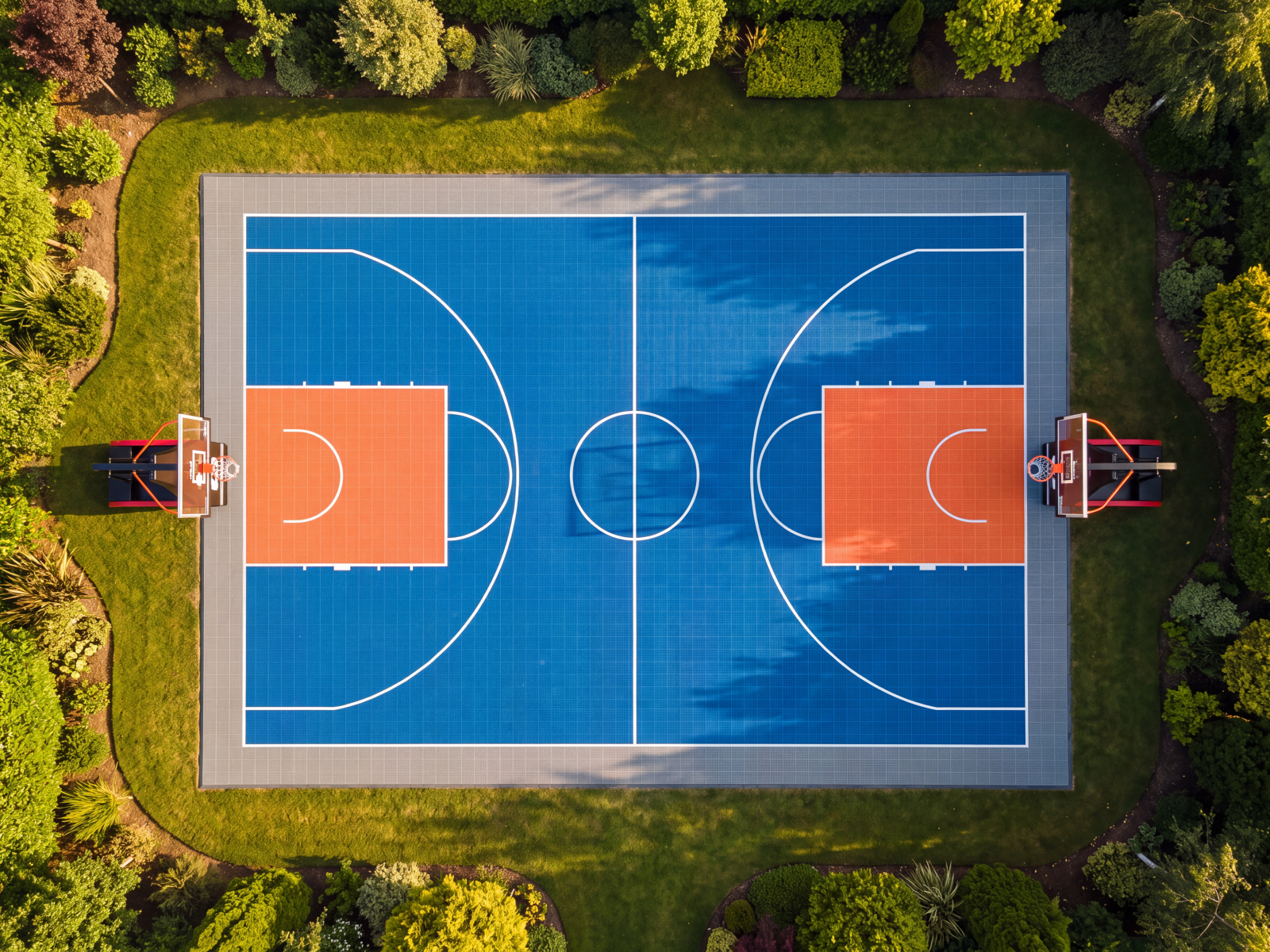 Vista aérea de una pista de baloncesto exterior de suelo modular azul y naranja rodeada de jardín